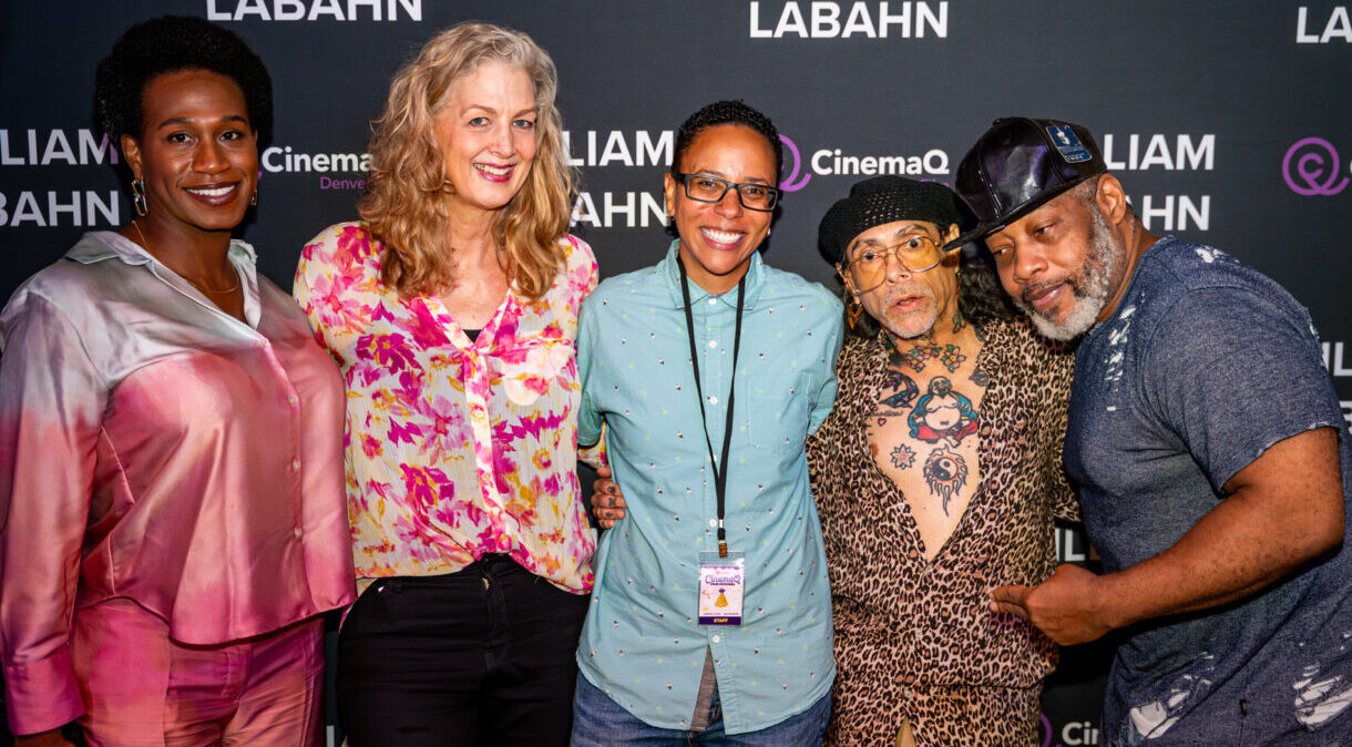 Five people smiling at a CinemaQ event, standing together against a branded backdrop