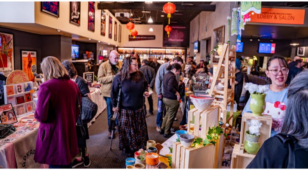 People browsing a bustling indoor market with colorful decor and various stalls displaying crafts and merchandise