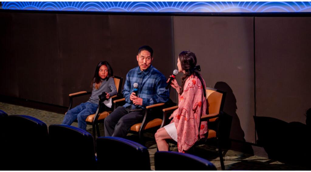 Three people sitting on stage during a discussion or interview