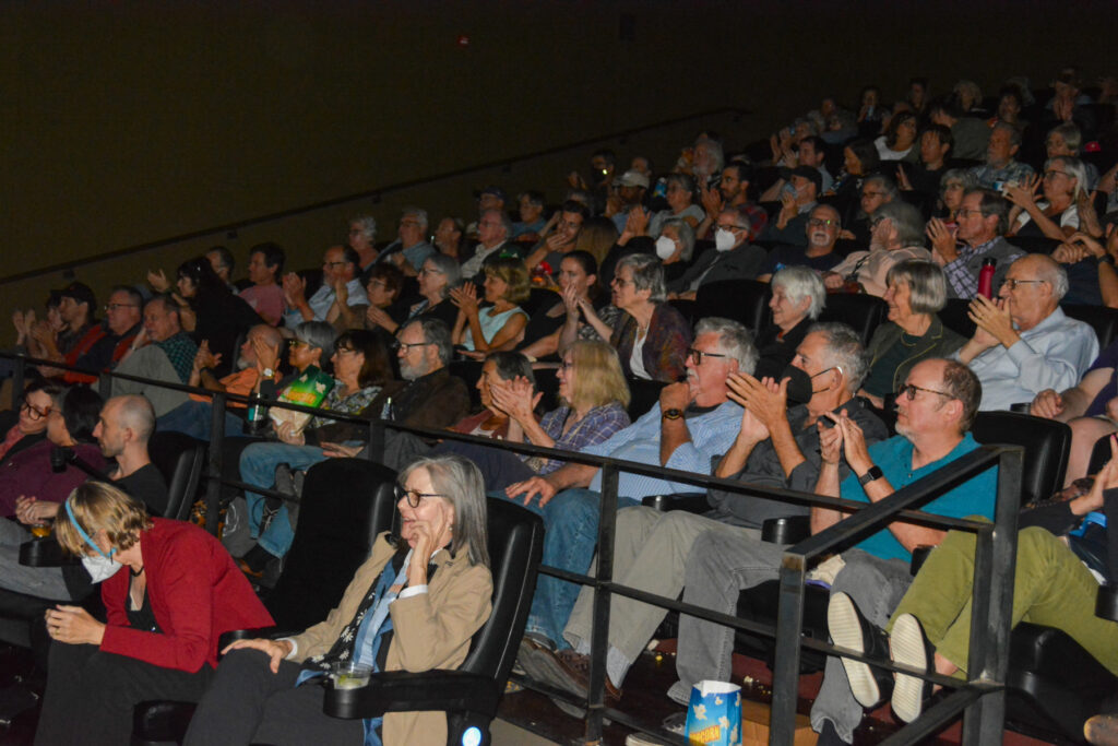 Audience clapping in a theater setting, showing appreciation during an event