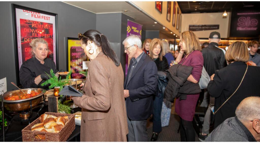 People gathering at a Denver Film Fest event with food and drinks available