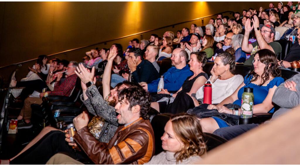Audience in a theater reacts with enthusiasm and cheering