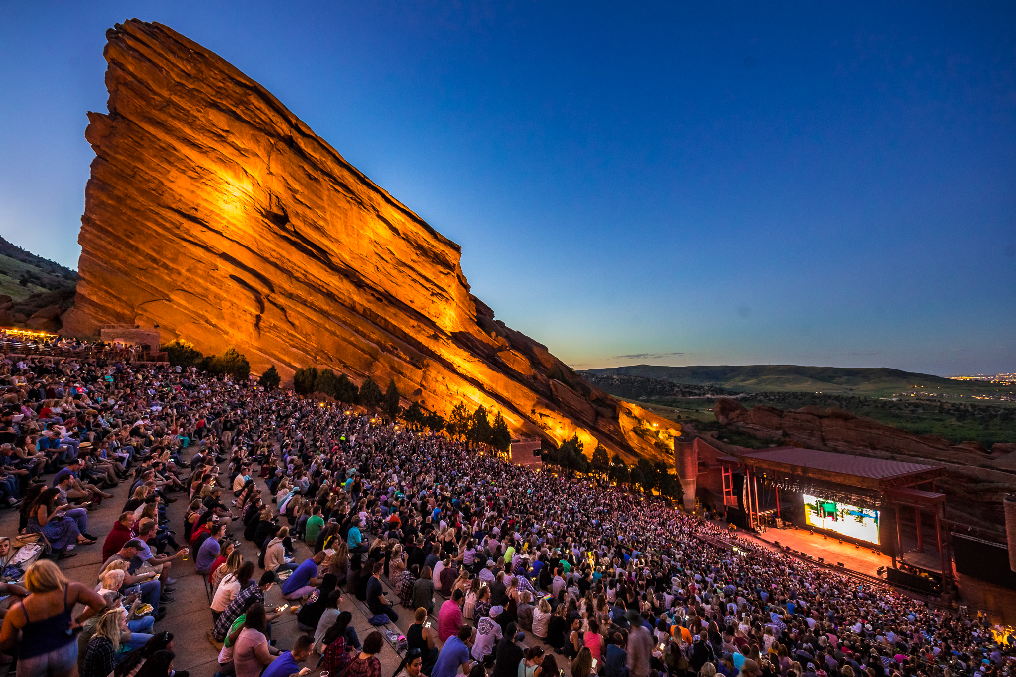 Crowd at Red Rocks Amphitheatre during a concert at sunset, with illuminated rock formations