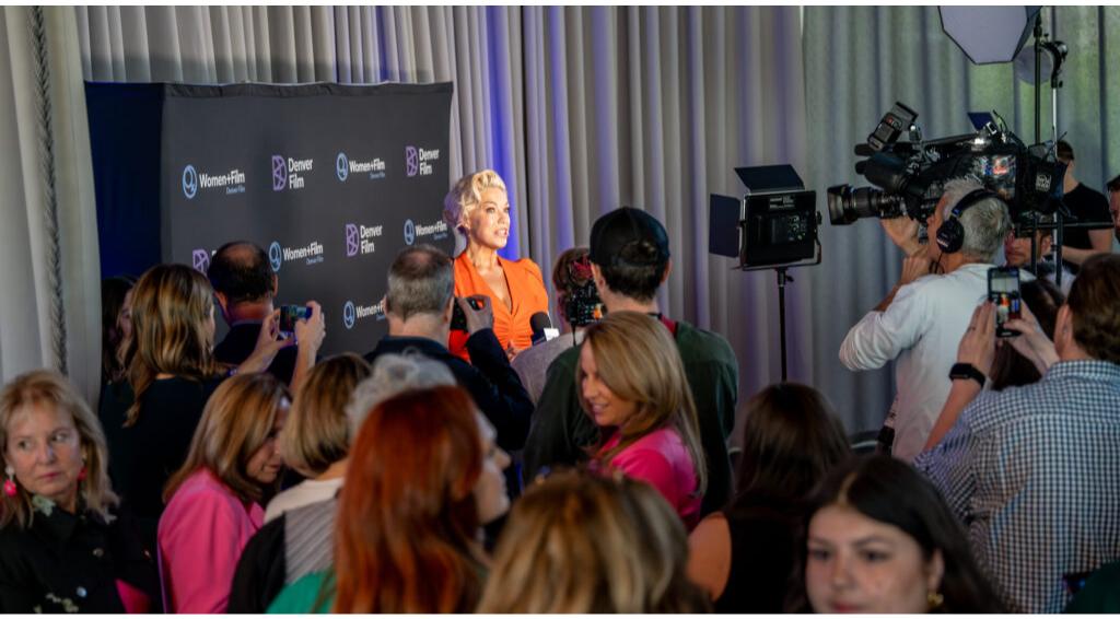 Hannah Waddingham being interviewed by media at Women+Film event, surrounded by photographers and attendees