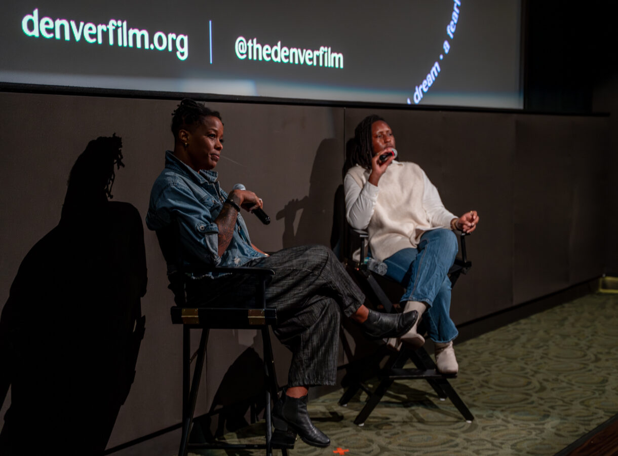 Two people speaking at a panel event, denverfilm.org displayed