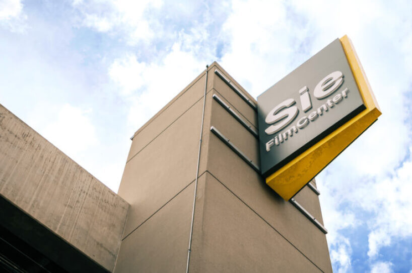Sie FilmCenter sign on a tall building with cloudy sky backdrop