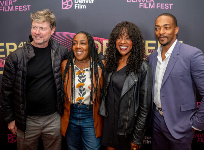 Four people smiling at Denver Film Festival event, posing in front of a branded backdrop