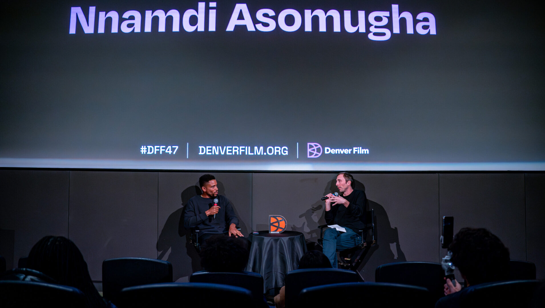 Nnamdi Asomugha speaking at Denver Film Festival event, #DFF47, with an interviewer in a theater setting