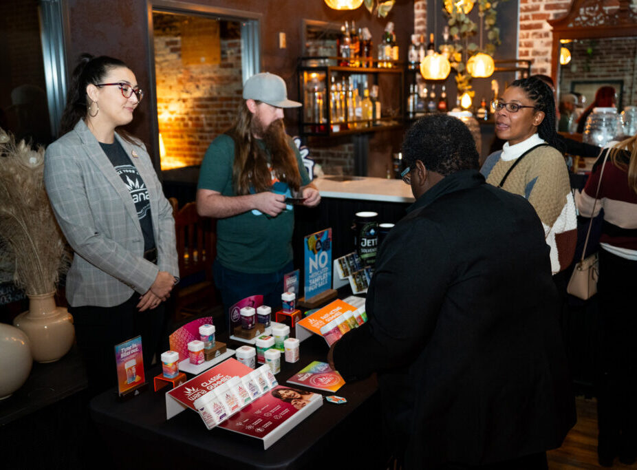 People interacting at a display table with products, in a warmly lit room