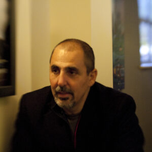 20111104_ItalianRecpt_043-300x300-1.jpg shows a man with short hair and a goatee, seated indoors, appearing thoughtful