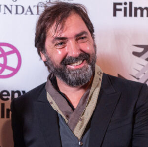 Person smiling at Denver Film Festival's Italian Showcase red carpet, wearing a suit with scarf