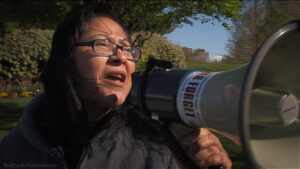 A person passionately speaks into a megaphone during a protest