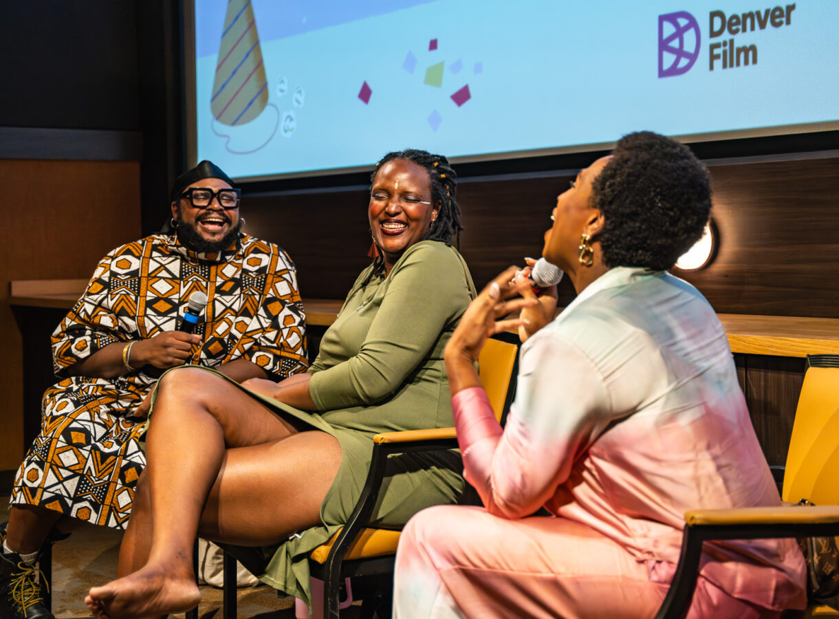 Three people laughing on stage during a Denver Film event
