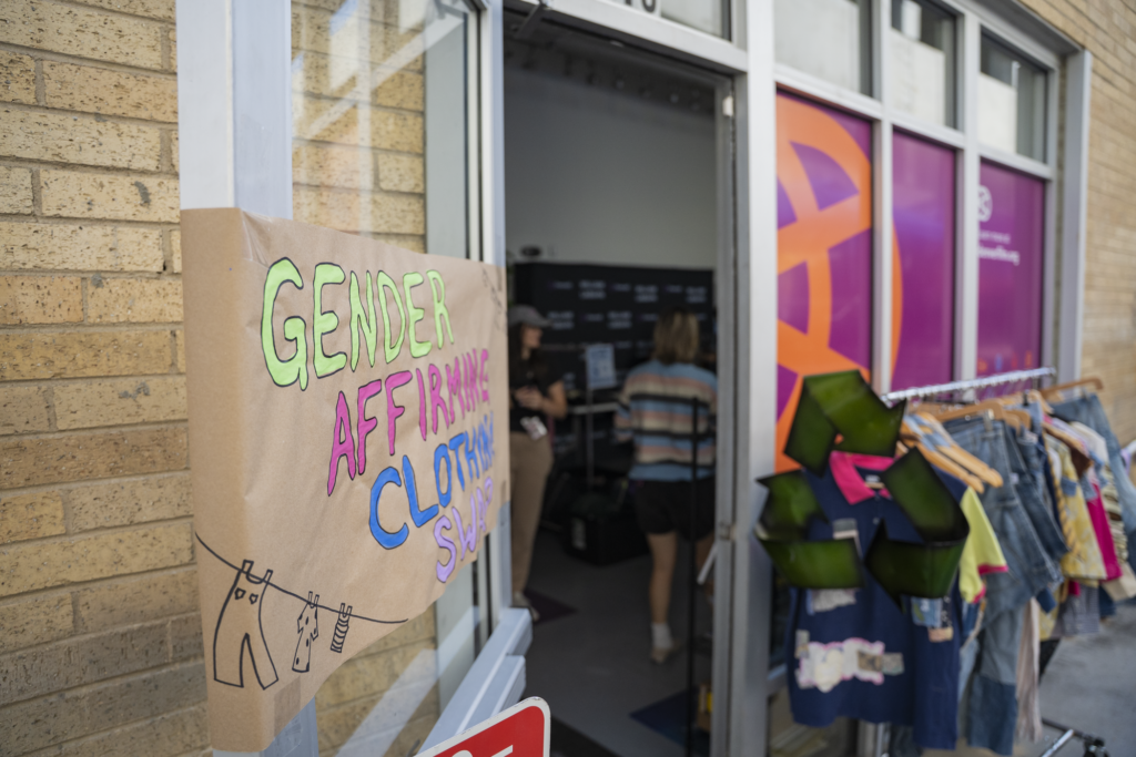 Gender Affirming Clothing Swap sign outside event with clothing rack