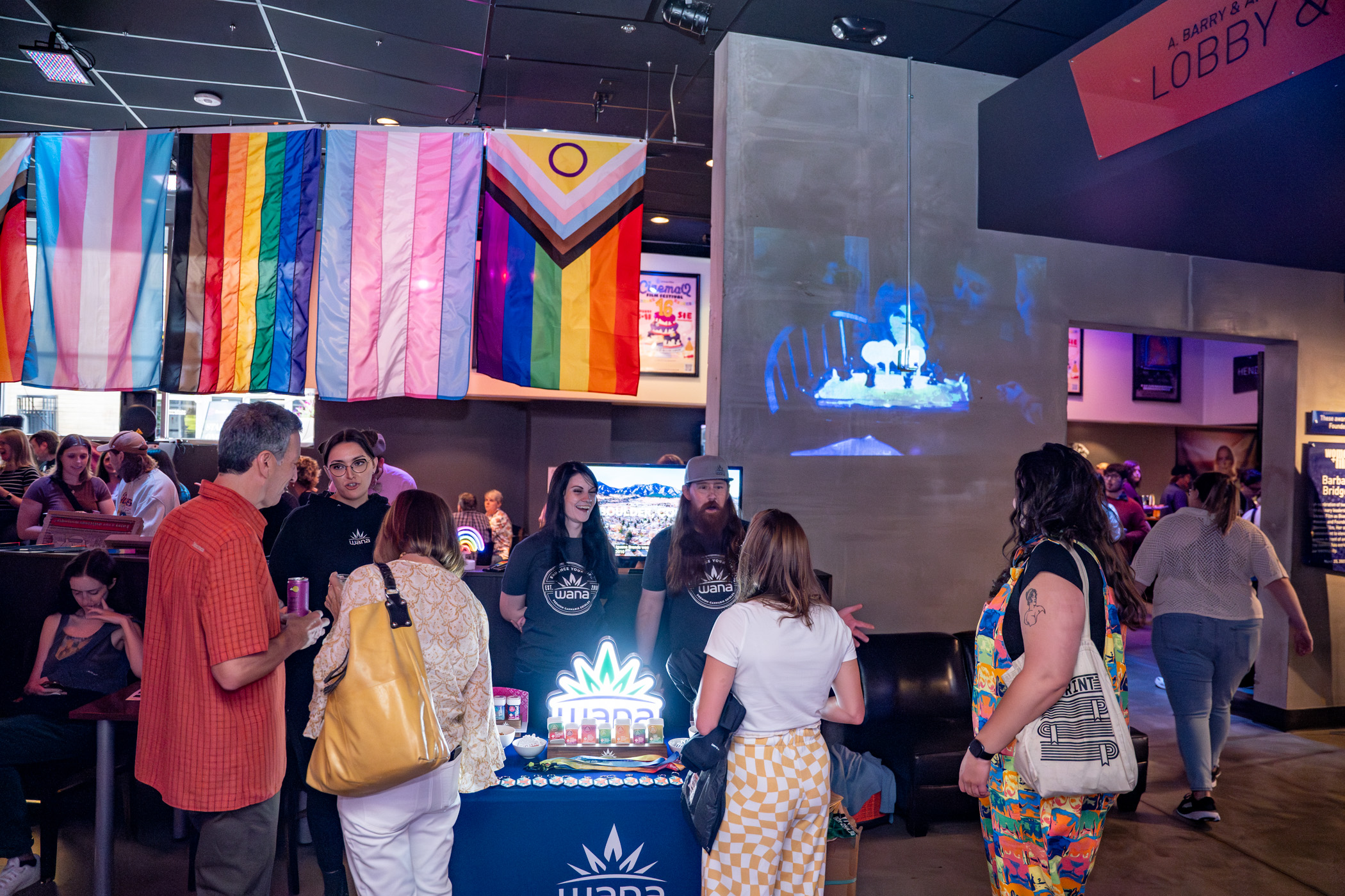 People engaged in conversation at an event under Pride flags