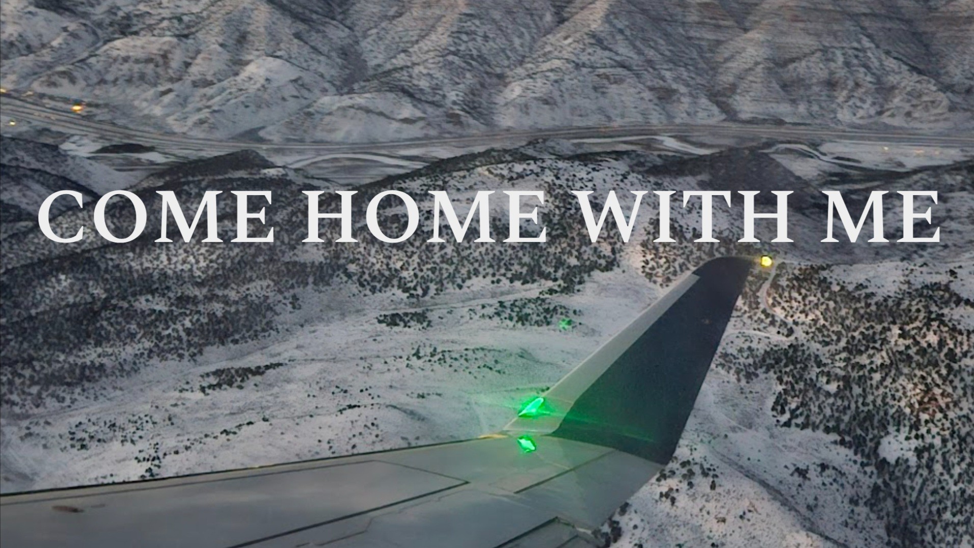 Airplane wing over snowy mountains with text: "COME HOME WITH ME"