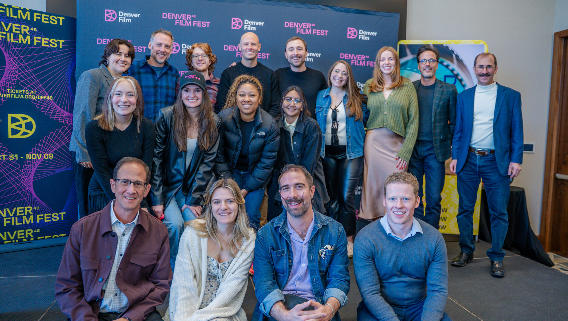 Group of people smiling at the Denver Film Fest backdrop displaying festival logos