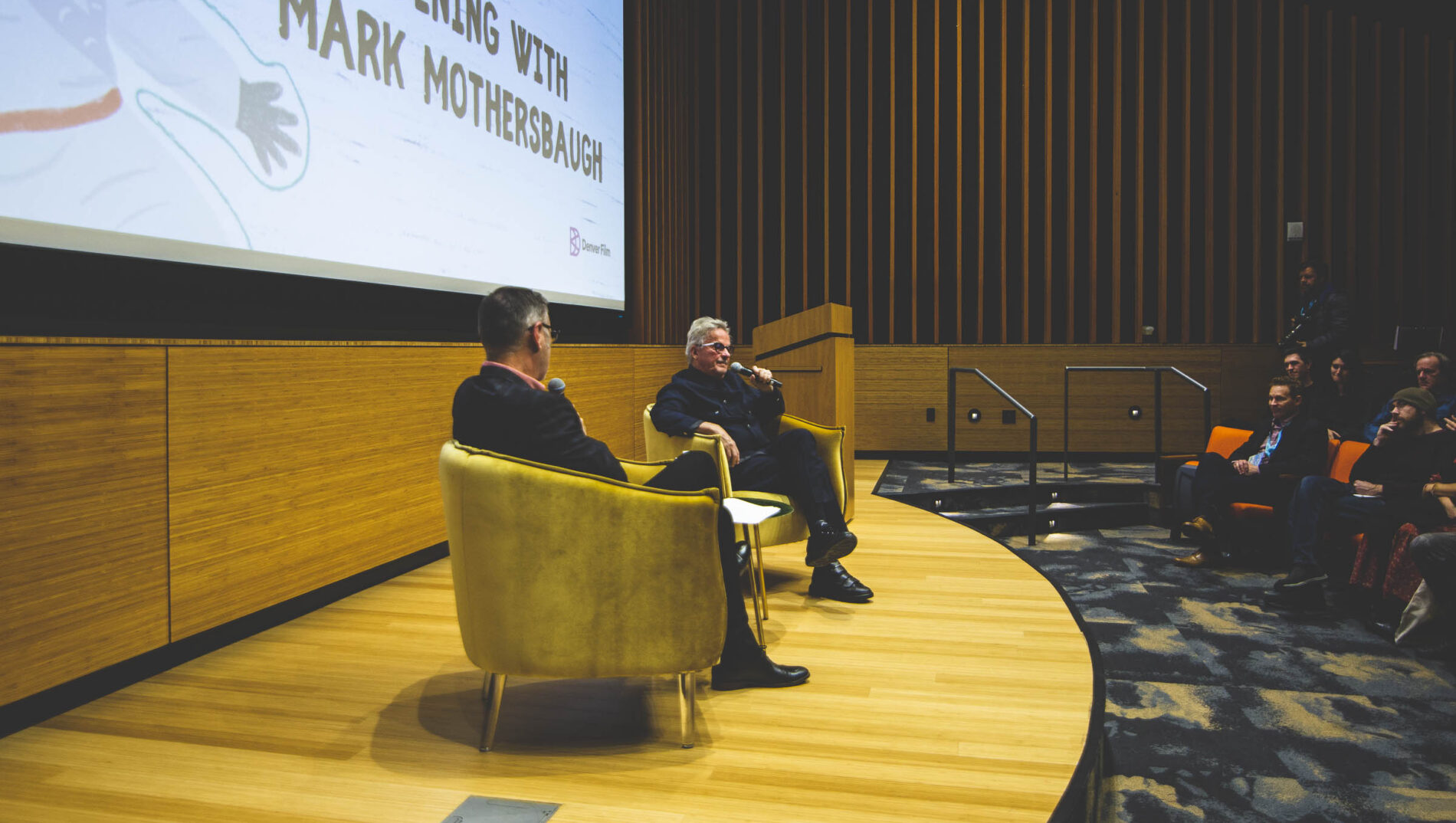Mark Mothersbaugh speaking on stage at "An Evening with Mark Mothersbaugh" event