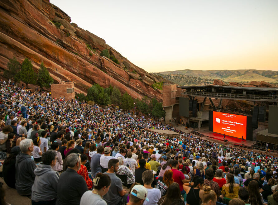 Large crowd at outdoor amphitheater, Red Rocks, watching presentation at sunset