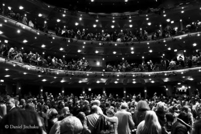 Black and white image of a crowded theater audience during a performance