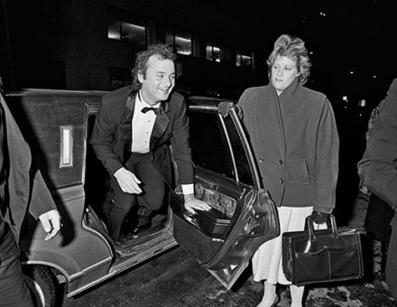 Bill Murray stepping out of a car in formal attire, woman holding handbag nearby