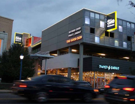 Twilight view of Sie FilmCenter with marquee displaying "Battered Cover Twist & Shout The Good Son" and nearby Twist & Shout store
