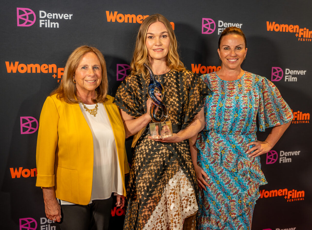 Three women at Women+Film Festival, with one holding an award