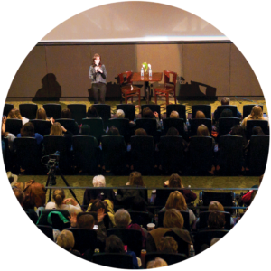 Projects speaking to a seated audience in a theater setting