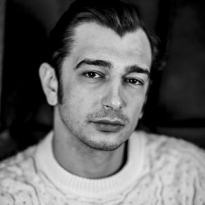 Stefano Cipani looking serious, wearing a textured sweater in a black-and-white portrait