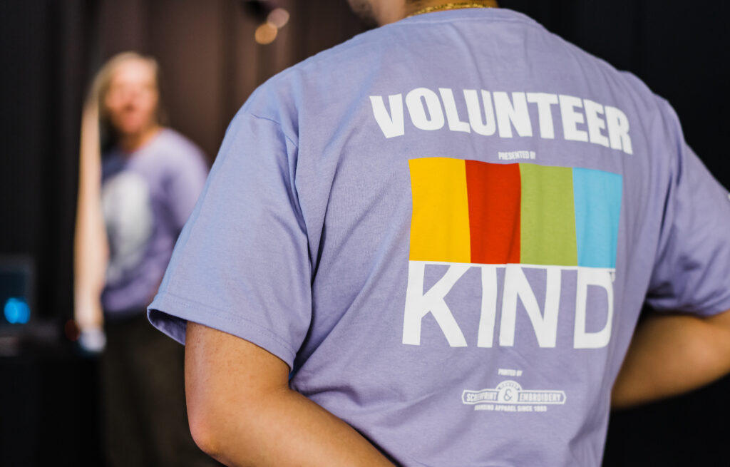 Support-Volunteer-2 in purple shirt with "VOLUNTEER KIND" text and colorful stripes. Logo: From The Hip Photo