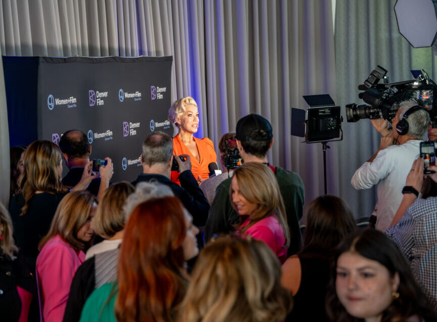 Hannah Waddingham speaks to media at a Denver Film event, surrounded by cameras and reporters