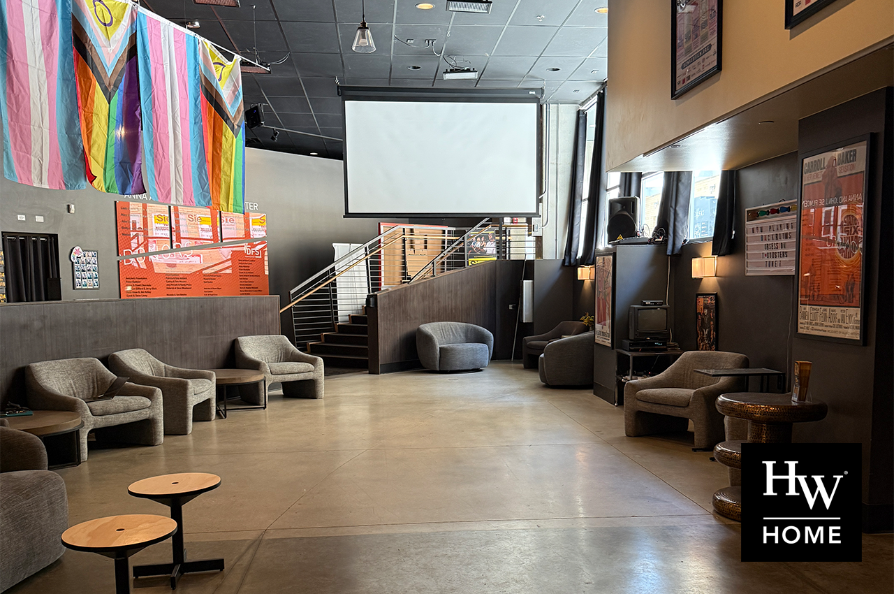 Renovated lounge with flags, projector screen, and HW Home logo