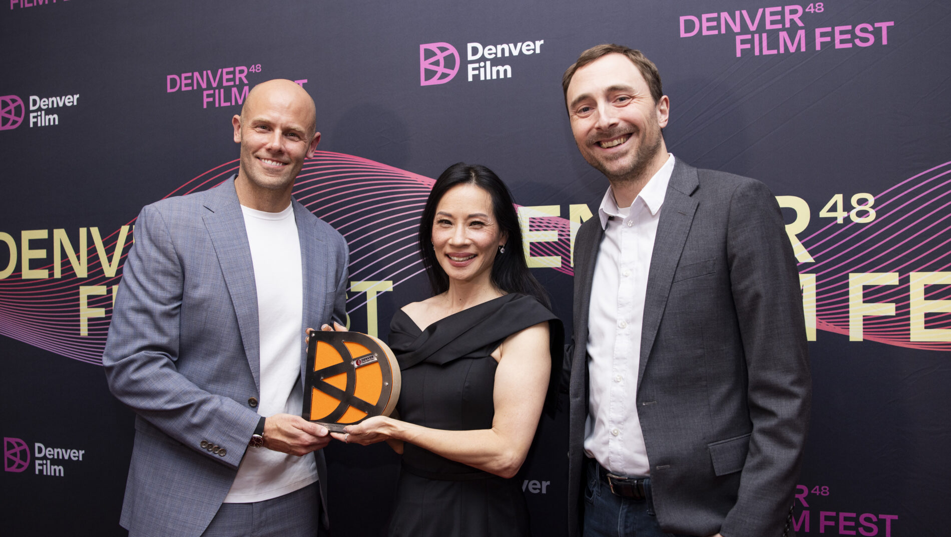 [gpt-4o]: Three people smiling at Denver Film Fest, one holding a trophy