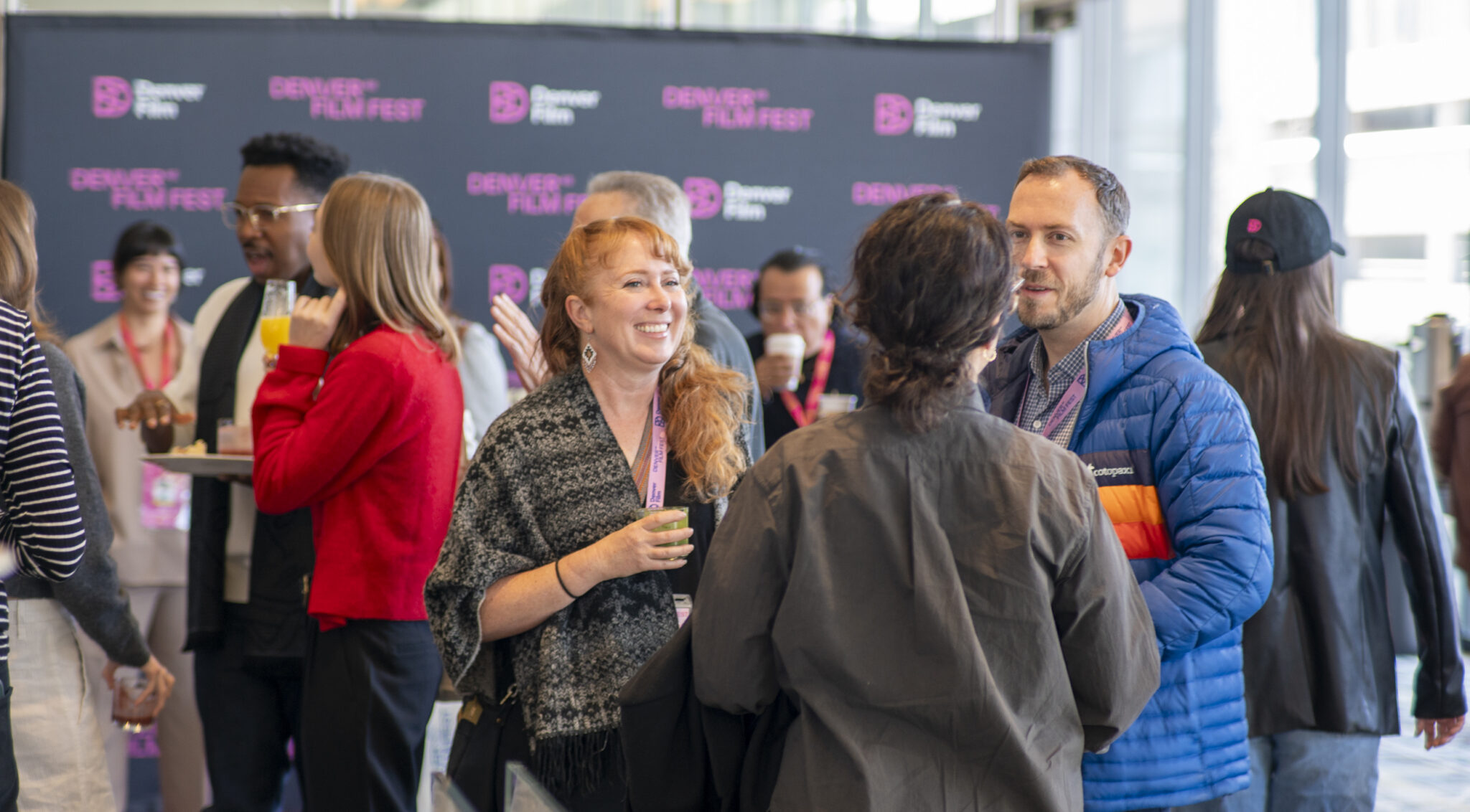 [gpt-4o]: People socializing at Denver Film Fest event, smiling and holding drinks