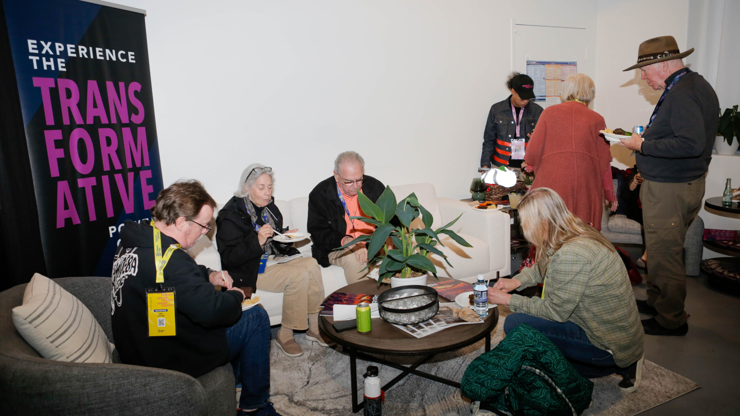 People socializing in a lounge with a banner reading "Experience the Transformative Power."