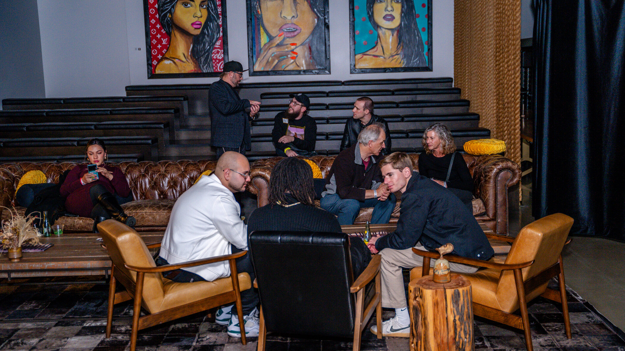People socializing in a lounge with vibrant portraits on the wall