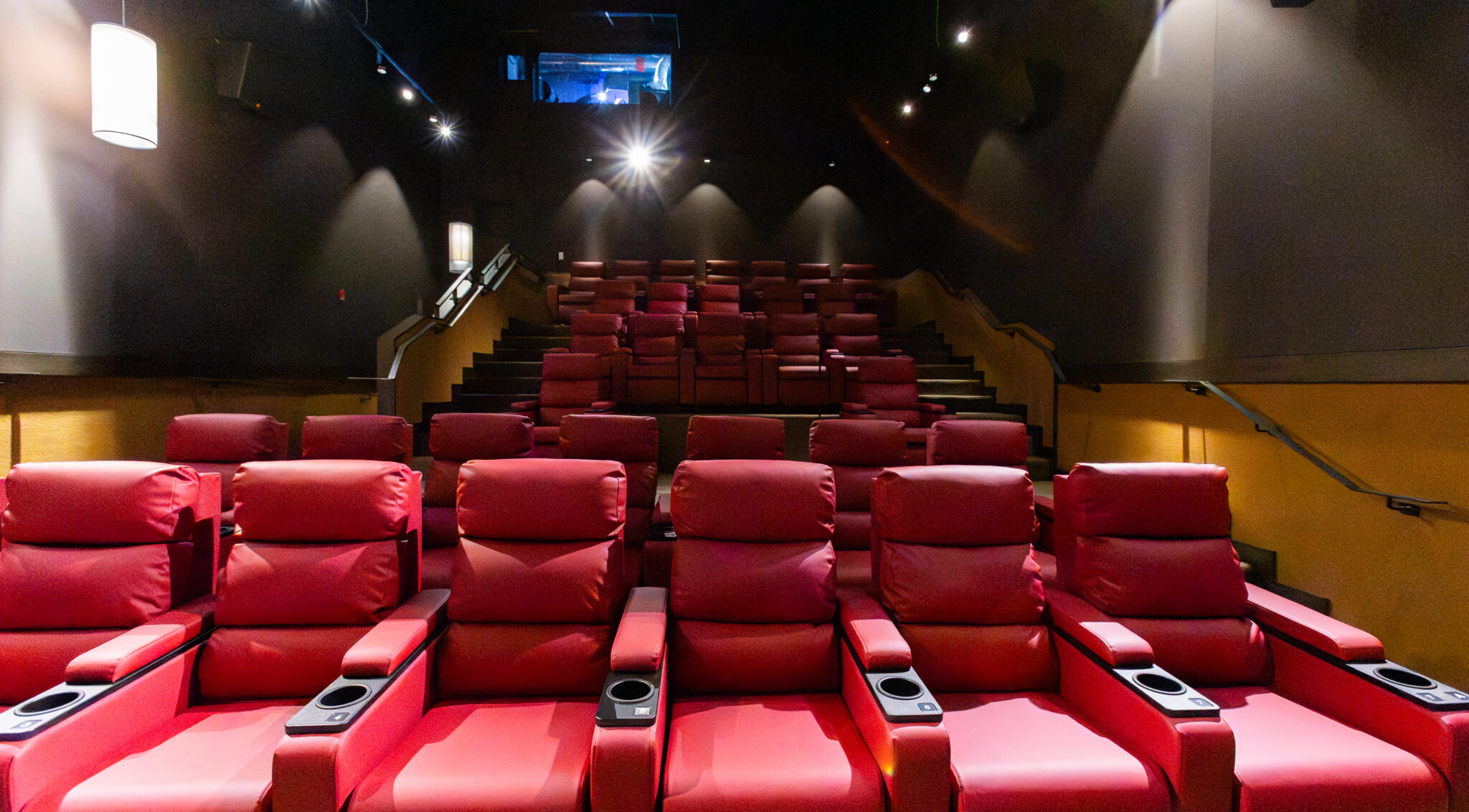[gpt-4o]: Red recliner seats in an empty movie theater with dim lighting
