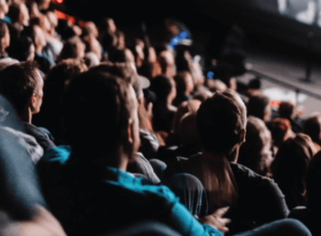 [gpt-4o]: Blurred audience seated in a large theater, focused on an unseen performance
