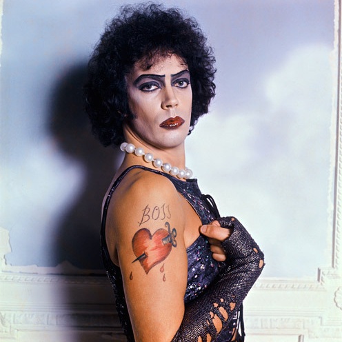 [gpt-4o]: Person with bold makeup and pearl necklace, showing tattoo on arm reading "Boss" with a heart