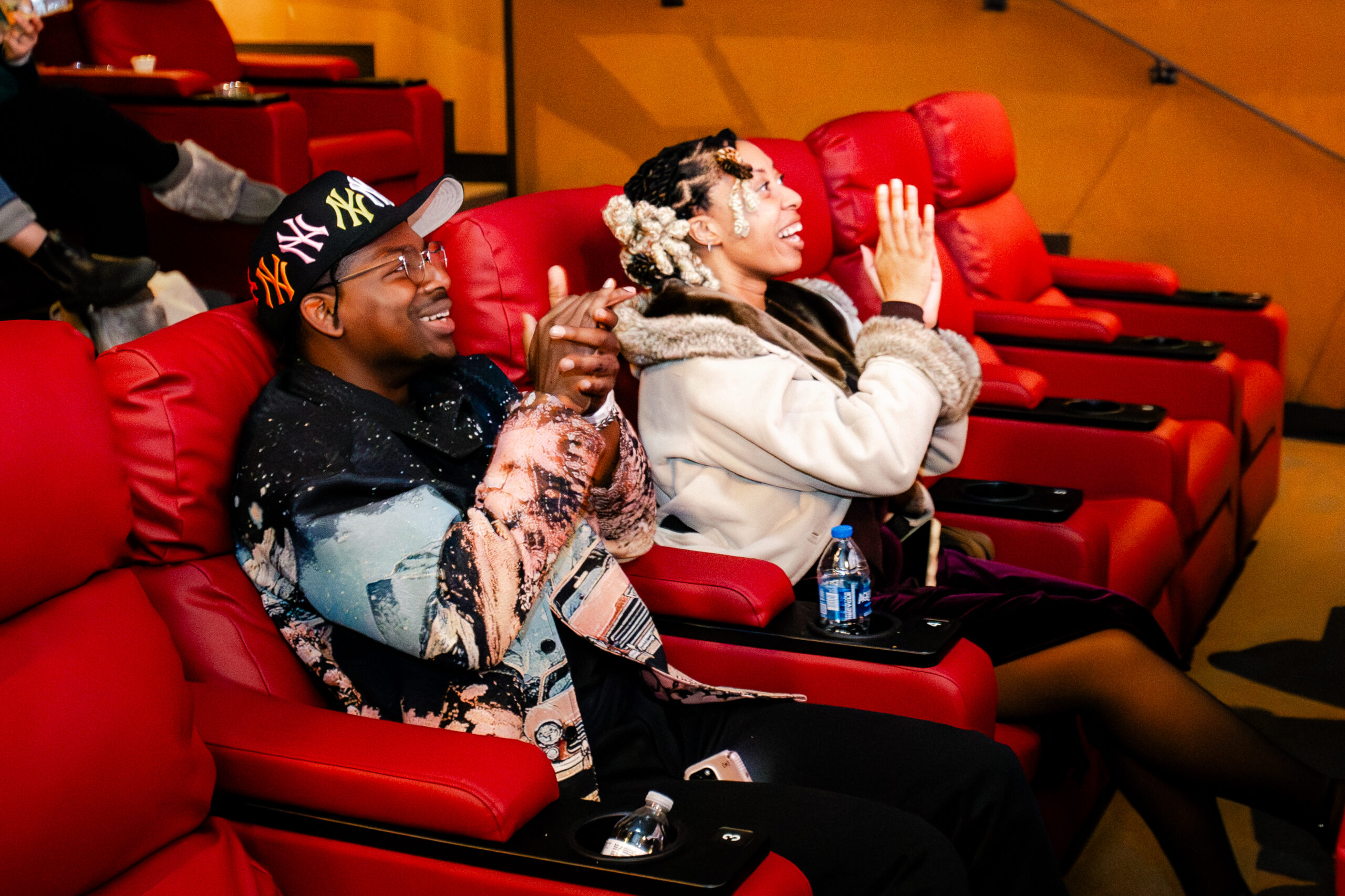 [gpt-4o]: People in theater chairs clapping and smiling, wearing colorful attire