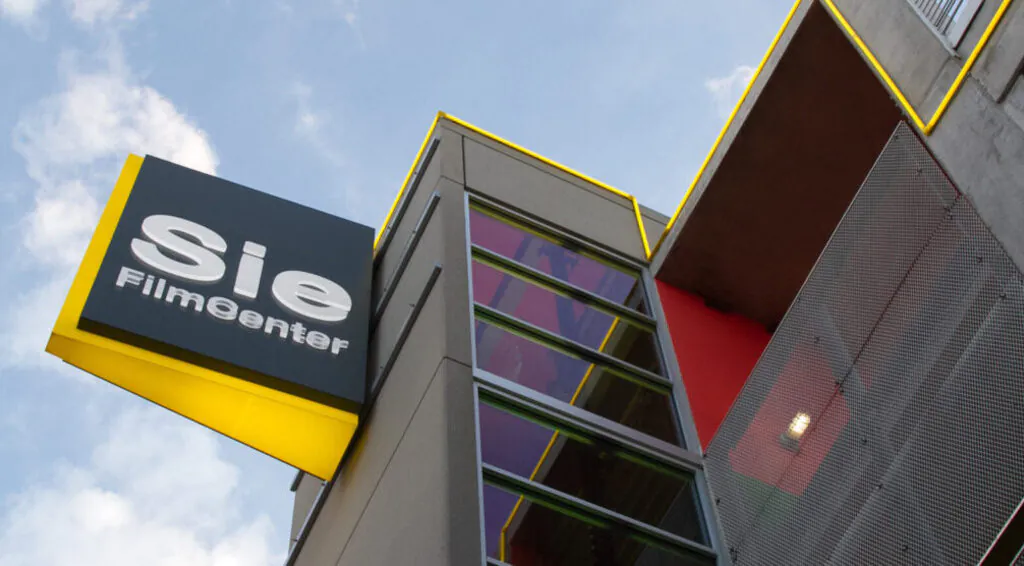 [gpt-4o]: Sie FilmCenter building with modern architecture, yellow accents, and clear blue sky